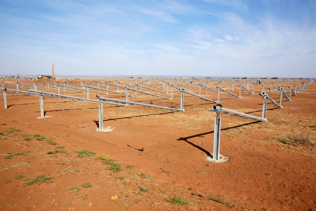 Ein großes Feld mit Solaranlagen für Solarenergie im Bau auf roter Erde