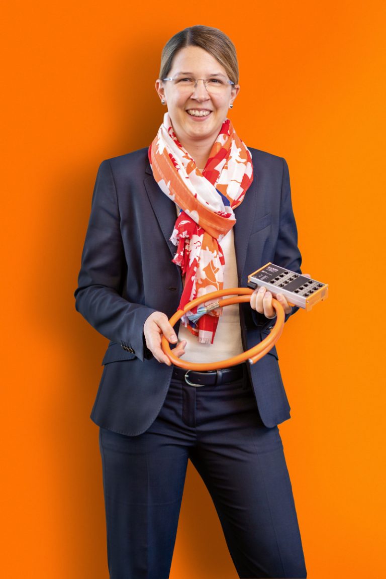 A smiling business woman holds a cable in her hand and looks into the camera