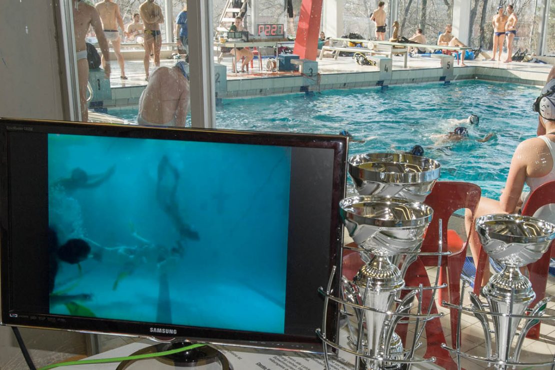 The video transmission of the underwater rugby tournament is shown on a monitor.