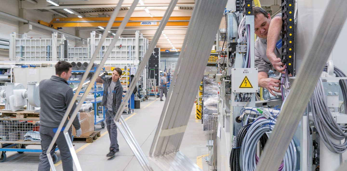 Man sieht die Mitarbeiter bei der Arbeit in der Fabrikationshalle von Bystronic glass in Baden-Württemberg.