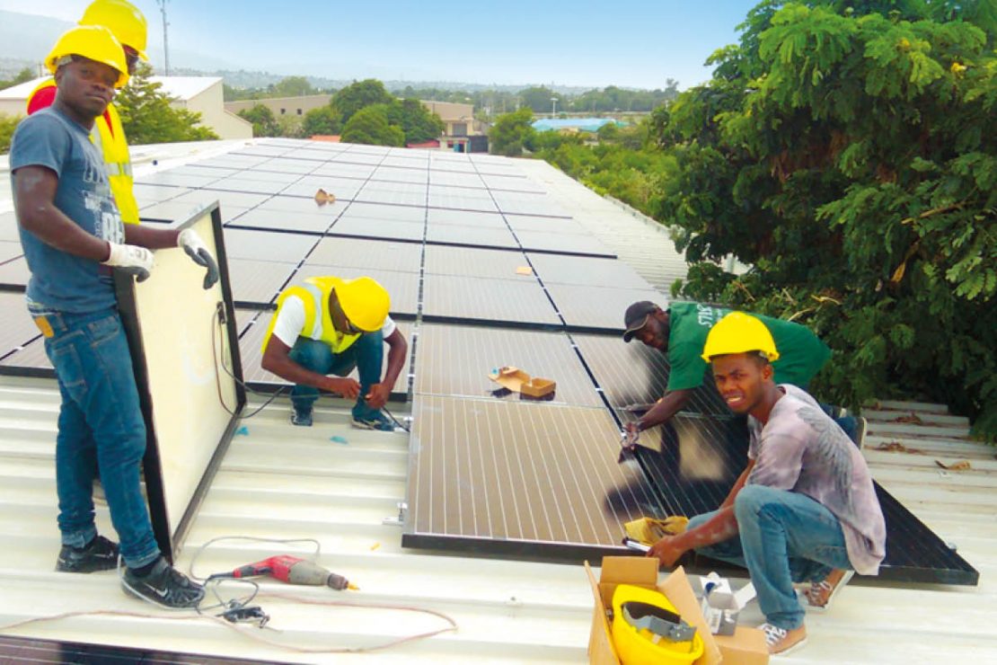 You can see workers on a roof assembling the “Solar Smart Grid” modules.