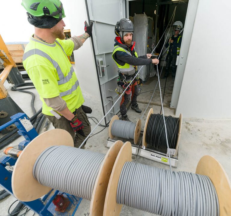Workers lay cables in a wind turbine