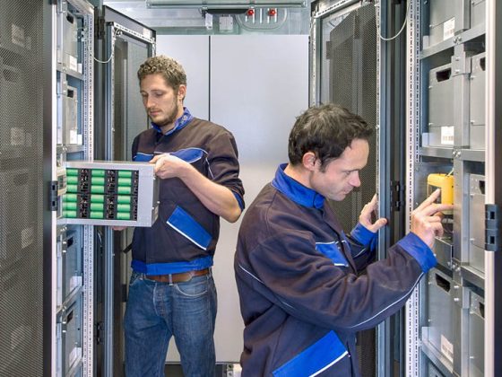 Auf dem Bild sieht man zwei Mitarbeiter arbeiten in einem Serverraum.