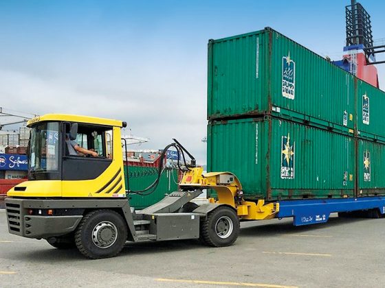 Auf dem Bild sieht man einen LKW beladen mit vier Container, der auf eine Fähre fährt.