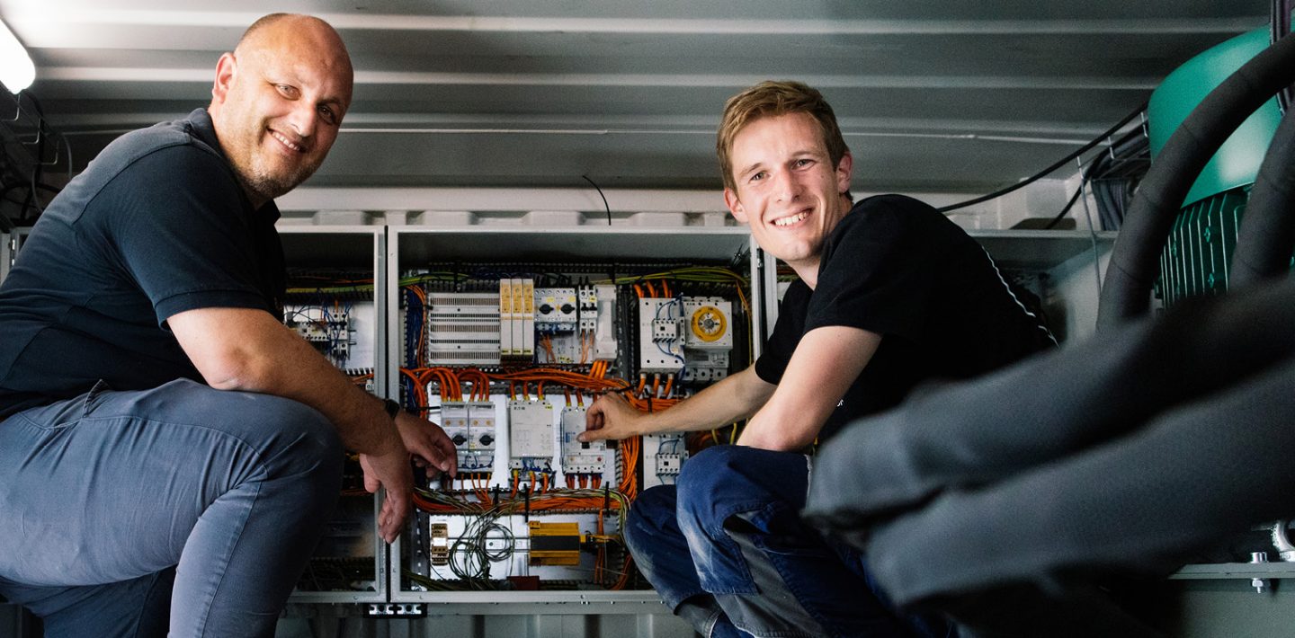 Auf dem Bild sieht man Johannes Drexler, TUM Boring Team (rechts) und Alois Heimler, LAPP Business Development Manager Automotive (links) vor dem Schaltschrank der Tunnelbohrmaschine.