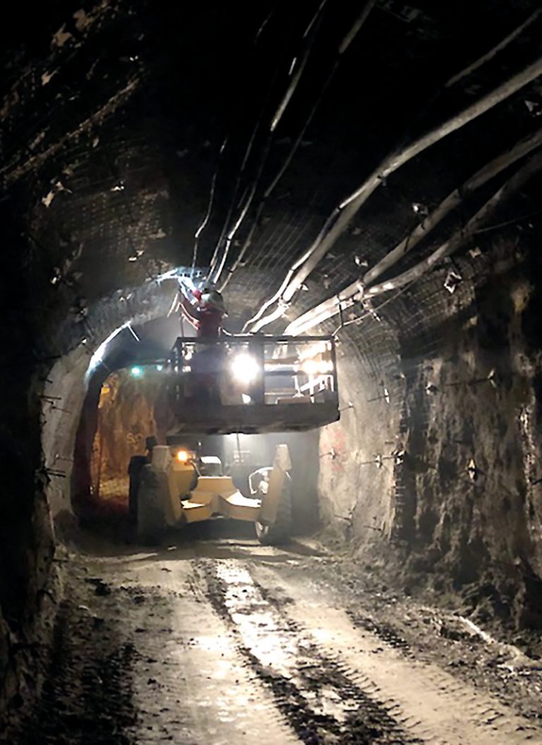 The picture shows a worker installing an intelligent lighting system in an underground mine.
