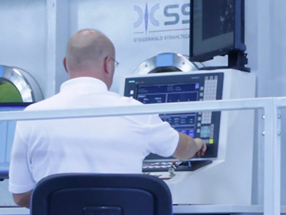 Das Bild zeigt einen Mitarbeiter bei der Bedienung vor einer Elektronenstrahl-Schweißmaschine von Steigerwald Strahltechnik (SST).