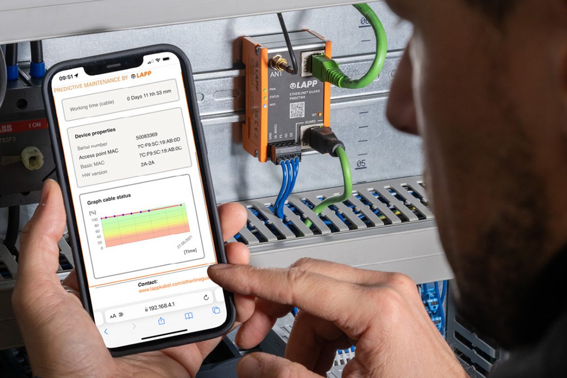 The picture shows the ETHERLINE® GUARD being used to monitor cables, with the evaluation being displayed on a smartphone.