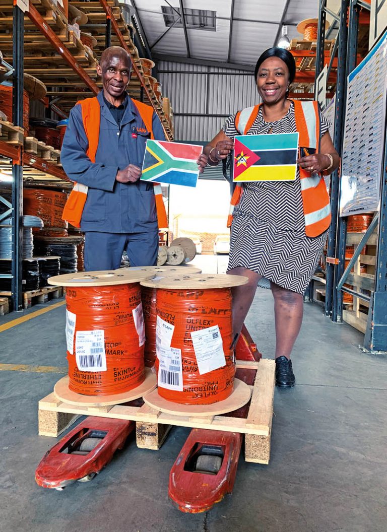 The picture shows two employees from LAPP Southern Africa with flags in their hands standing in front of three cable drums in the warehouse.