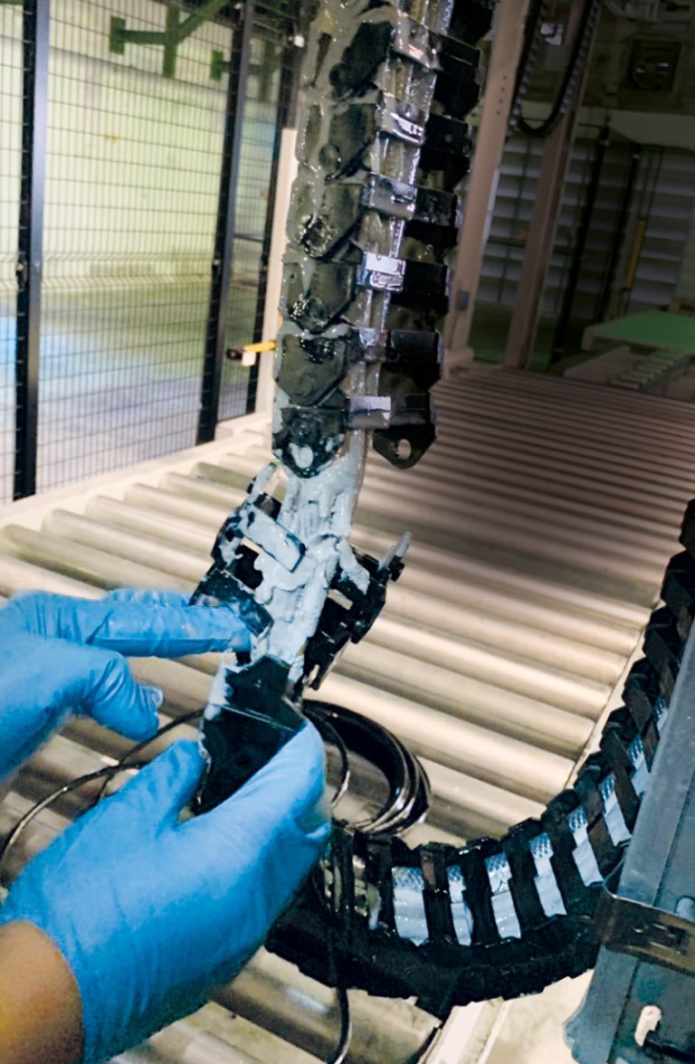 Das Bild zeigt eine Schleppkette in einem Produktionsbetrieb, die verschmierte und beschädigte Kabel enthält.