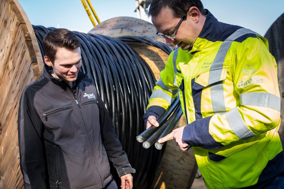 The picture shows two employees from Stadtwerke Tübingen showing a cable with an aluminum core.