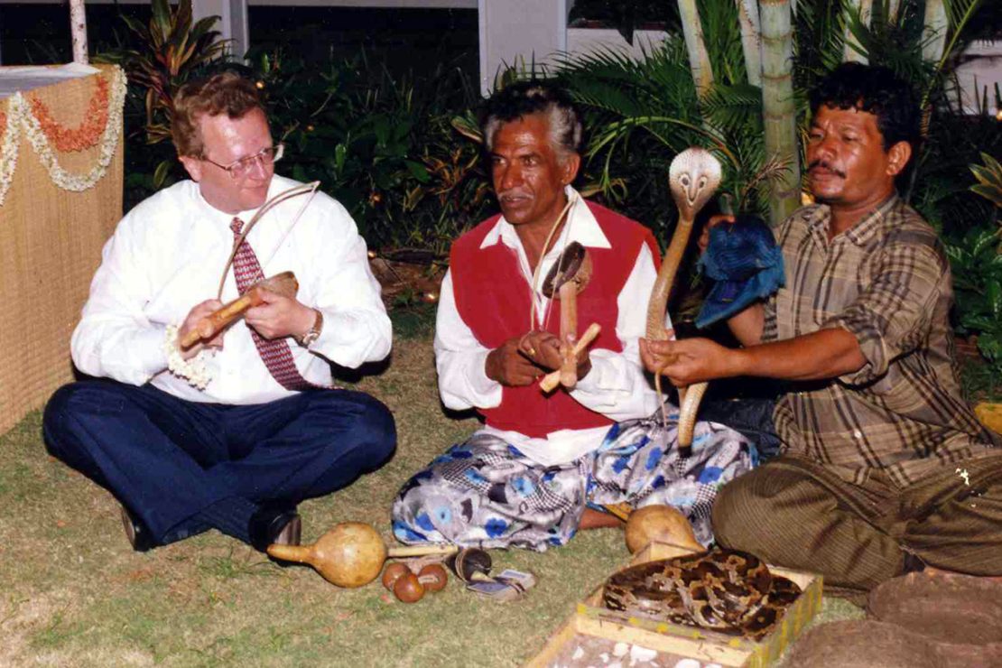 The picture shows Andreas Lapp and two snake charmers sitting on the floor in front of two snakes.