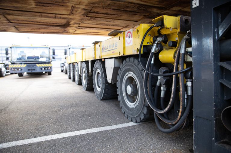 Das Bild zeigt die modularen Schwerlasttransporter der TII Group aus der Nähe, die ein Gewicht tragen.