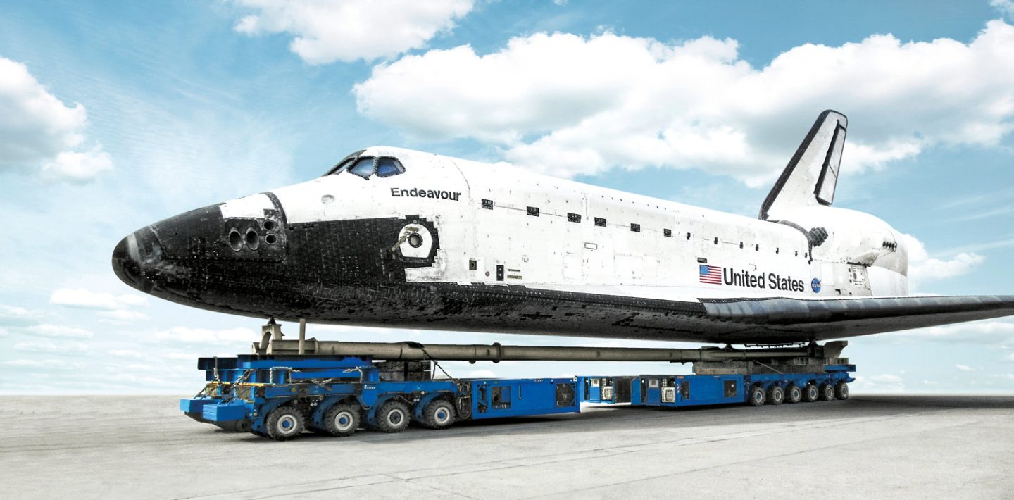 Auf dem Bild sieht man das amerikanische Spaceshuttle „Endeavour“ wie es auf den modularen Schwerlasttransporter der TII Group transportiert wird.