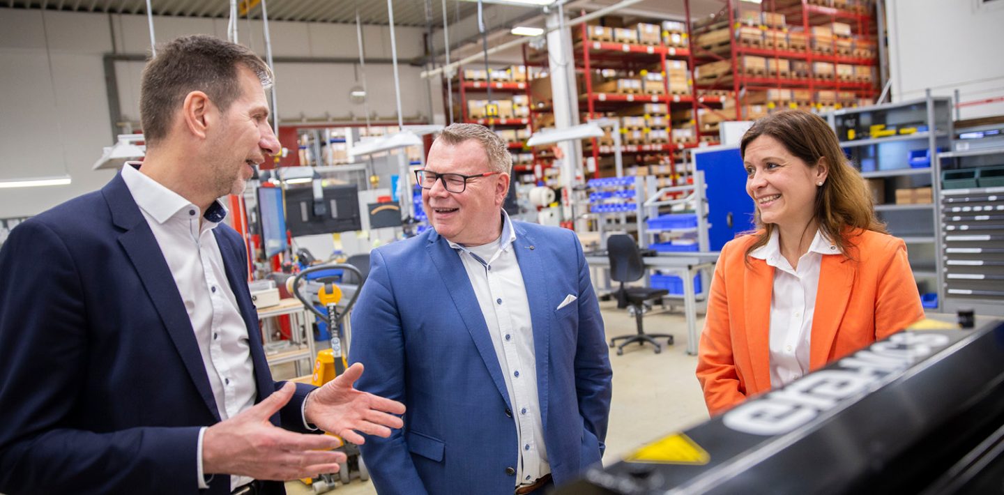 The picture shows Thorsten Grünberg – Industry Manager Train at U.I. LAPP GmbH, Ingolf Oßfeld – Global Head of Purchasing and Logistics at aichele GROUP GmbH + Co. KG and Bianca Feistel – Account Manager at U.I. LAPP GmbH in the production area at the site of era-contact GmbH in Bretten-Gölshausen.