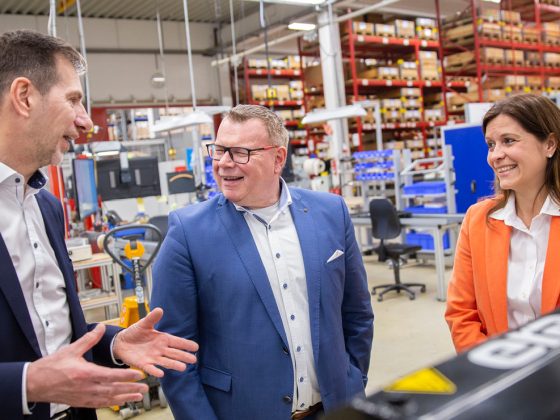 The picture shows Thorsten Grünberg – Industry Manager Train at U.I. LAPP GmbH, Ingolf Oßfeld – Global Head of Purchasing and Logistics at aichele GROUP GmbH + Co. KG and Bianca Feistel – Account Manager at U.I. LAPP GmbH in the production area at the site of era-contact GmbH in Bretten-Gölshausen.